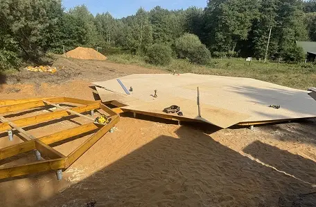 Budowa jurty, etap 1: Przygotowanie okrągłego, drewnianego podestu na płaskim, piaszczystym terenie.