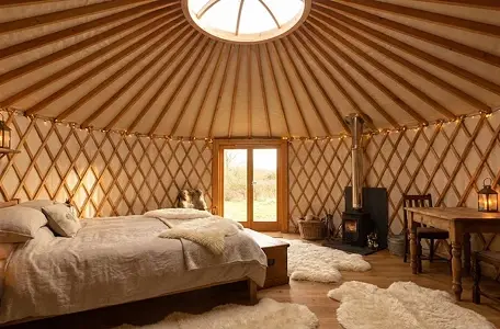 Wnętrze jurty, łóżko, stolik, dywany