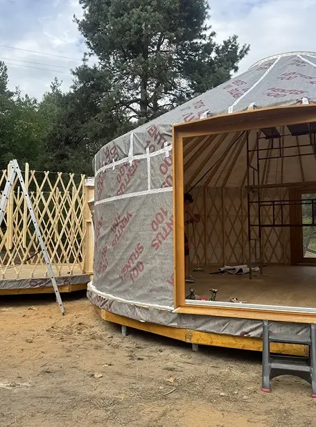 Budowa jurty, etap 3: Montaż drewnianego szkieletu ścian oraz izolacji paroprzepuszczalnej (folia typu "Stout"). Widoczne ościeżnice drzwi i okien.